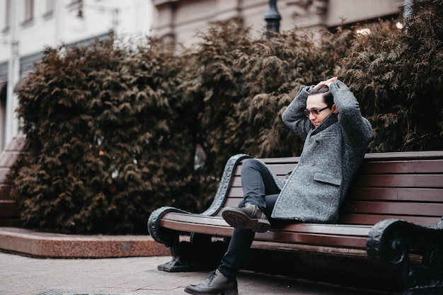 stylish man in a gray coat and sunglasses walking in the city.