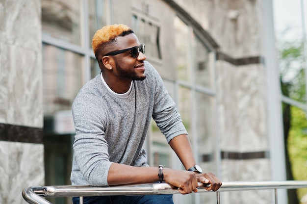 Stylish man on gray sweater and black sunglasses posed at street