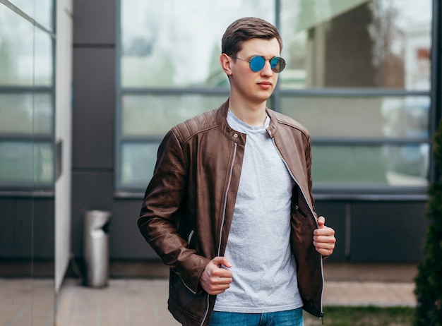 A stylish man in leather jacket, glasses and gray  T-shirt. Street photo