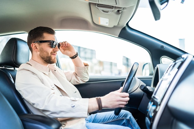 Stylish man in sunglasses driving car