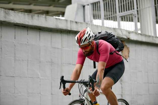 Stylish man walking around the city on bicycles on a weekend riding on a background of a gray wall