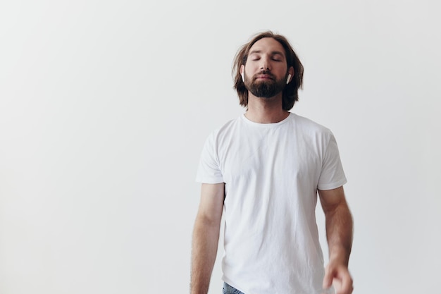 Stylish man in a white tshirt with wireless headphones in his ears having fun listening to music smile on a white background lifestyle