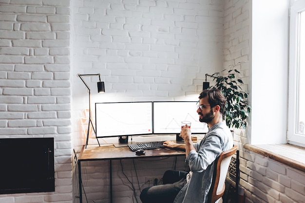 Stylish man working with a computer on two monitors designer or professional visualizer