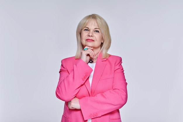 Stylish mature business woman looking at camera on light studio background