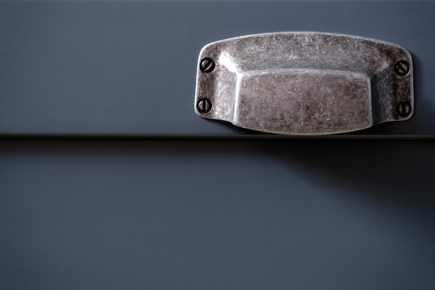 Stylish metal matte furniture handle on facade of gray kitchen cabinet selective focus