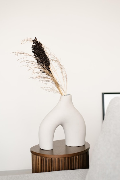 Stylish modern white ceramic vase interestingly shaped white ceramic vase with dried flowers in the decker of a Scandinavian living room or bedroom room