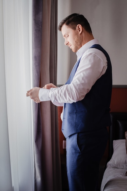 The stylish portrait of the groom preparing for the wedding ceremony in the morning. Morning of the groom. Morning preparation of the groom.