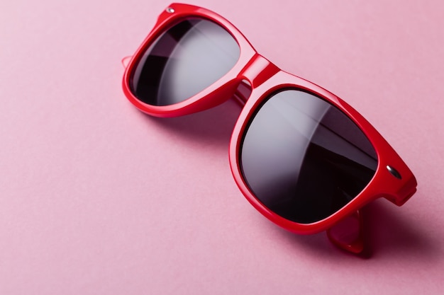 Stylish red sunglasses closeup on pink background. Bright, colorful fashion accessory, top view