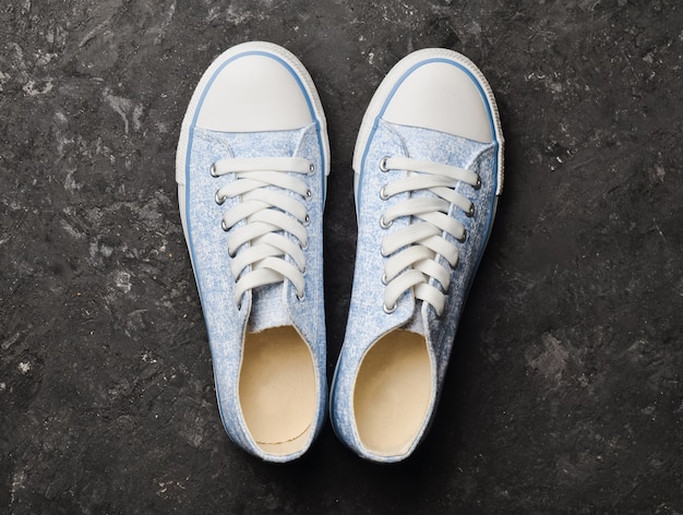 Stylish retro sneakers from 80s on a black concrete floor. Top view.