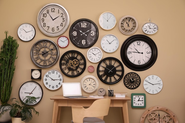 Photo stylish room interior with collection of wall clocks and workplace