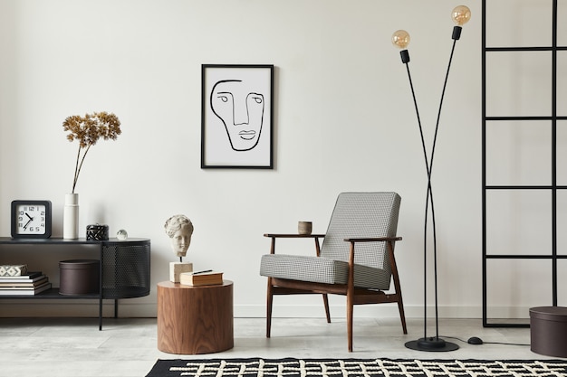 Stylish scandinavian composition of living room with design armchair, black frame, commode, wooden stool, book, decoration, loft wall and personal accessories in modern home decor.