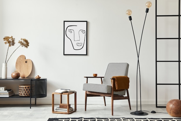 Stylish scandinavian composition of living room with design armchair, black frame, commode, wooden stool, lamp, decoration, loft wall and personal accessories in modern home decor.