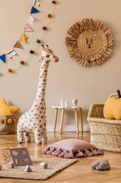 Stylish scandinavian interior of child room with natural toys, hanging decoration, design furniture, plush animals, teddy bears and accessories. Beige walls. Interior design of kid room.