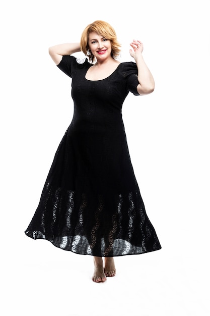 Stylish smiling middle-aged woman in a black flying dress on a white wall. Healthy lifestyle and activity. Vertical.