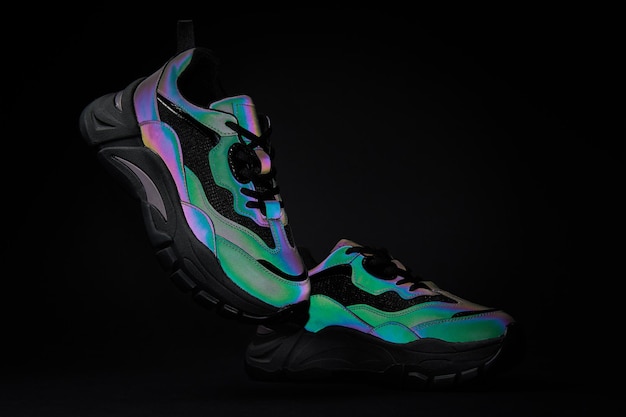 Stylish sneakers with neon gradient on black background pair of glowing creative fashion shoes