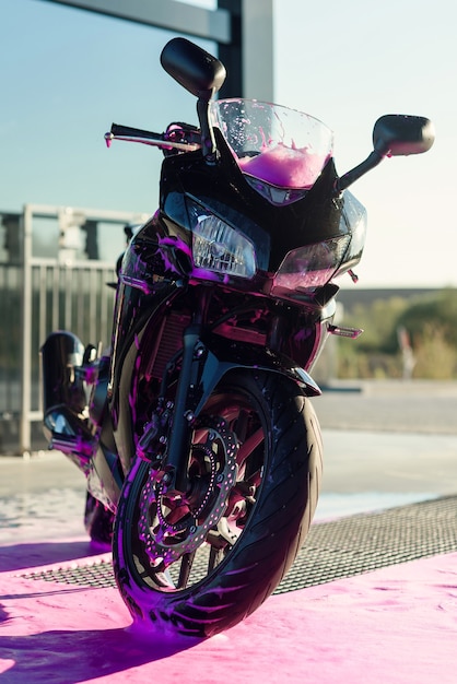 Stylish sports motorcycle with foam on the self-service car wash at sunrise.