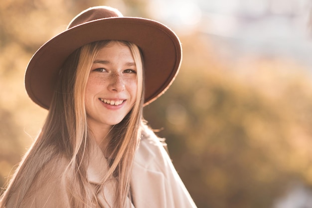 Stylish teen girl wearing hat and winter coat over nature background