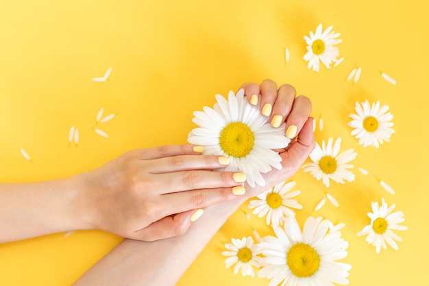 Stylish trendy female manicure. Beautiful young woman's hands on yellow background.