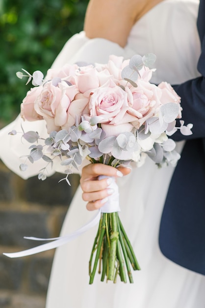 Stylish wedding bouquet of delicate pink roses in the hands of the bride closeup