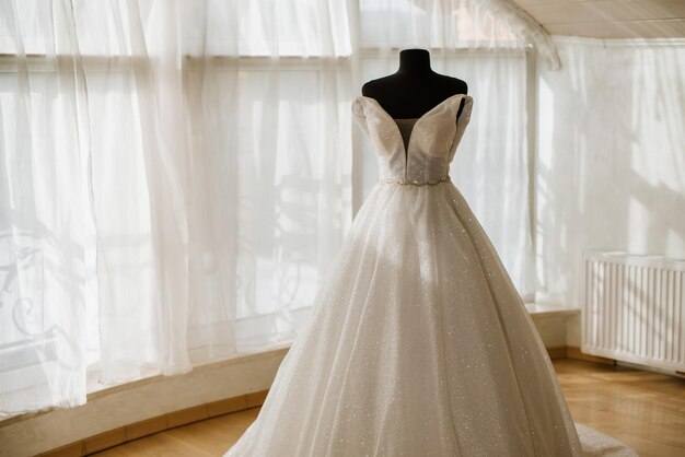 Stylish wedding dress on a mannequin in the morning by the window on the wedding day Preparing for the wedding day