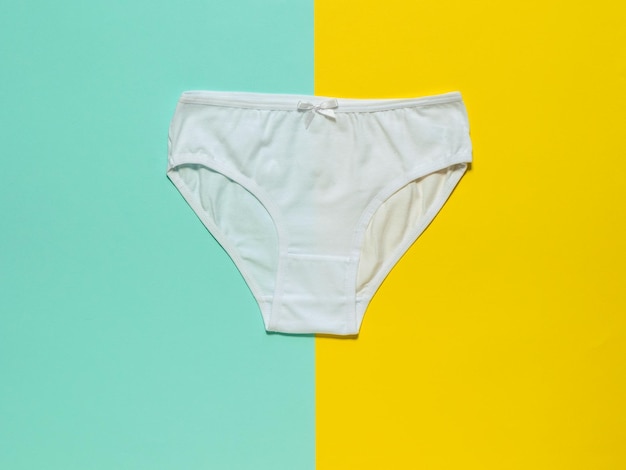 Stylish white women's panties on a yellow and turquoise background Flat lay