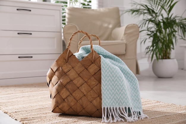 Photo stylish wicker basket with light blue scarf on floor indoors