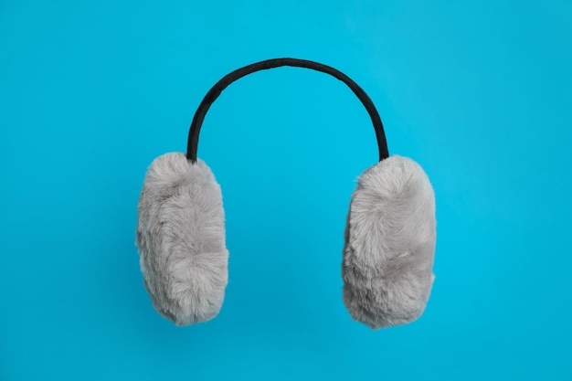 Stylish winter earmuffs on light blue background