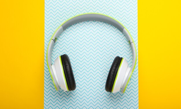 Stylish wireless stereo headphones on yellow blue pastel surface