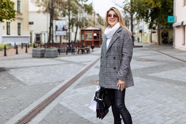 Stylish woman in autumn clothes walking around the city in sunglasses