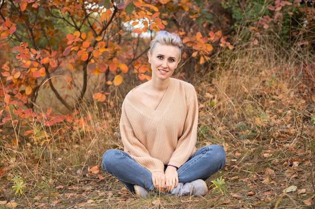 Stylish woman in autumn forest background with golden and red trees