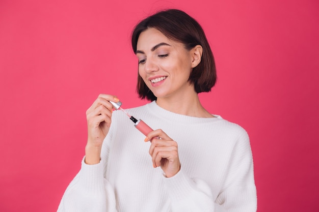 Stylish woman in casual white sweater on pink red wall