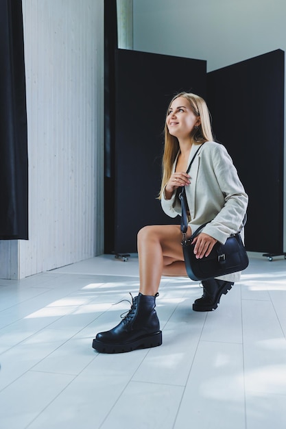 Stylish woman in classic beige clothes with trendy black leather bag in stylish shoes Beautiful female legs with black shoes in the studio