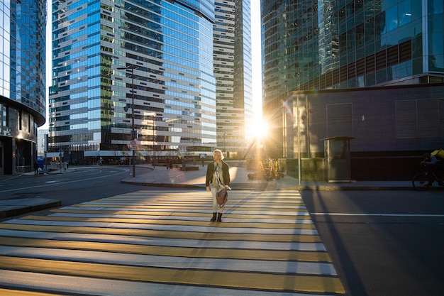 Stylish woman crossing road on zebra while walking outdoors