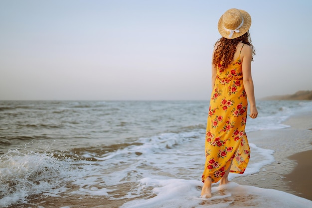 Stylish woman in elegant dress posing near the sea Summer time Travel weekend relax