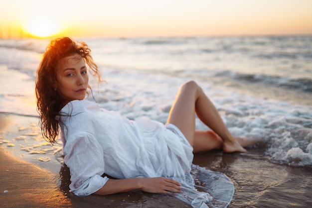 Stylish woman in elegant white dress posing near the sea Summer time Travel weekend relax