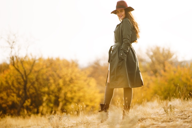 Stylish woman enjoying autumn weather in the meadow