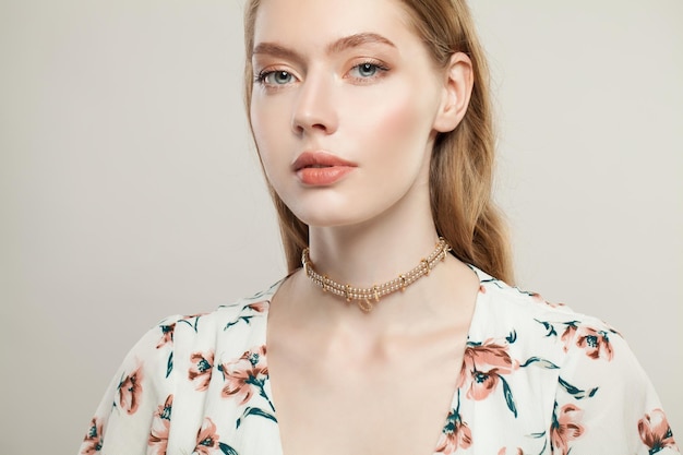 Stylish woman fashion model wearing luxurious golden necklace with pearls on white background