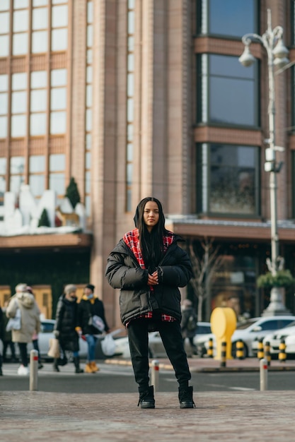 Stylish woman in fashionable oversize clothes stands on the street of the metropolis