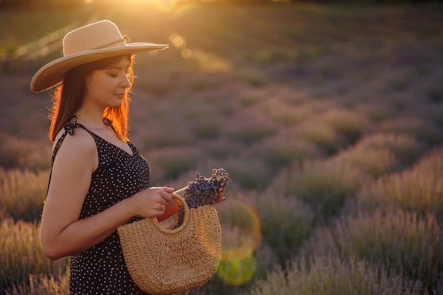 Stylish woman in lavender field with wicker bag