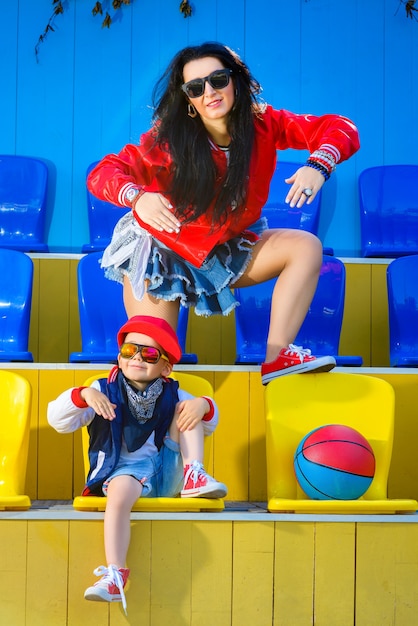 Stylish woman and little boy posing at basketball court.