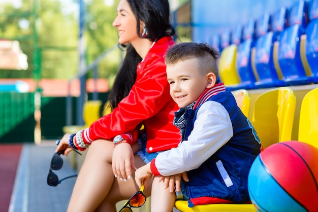 Stylish woman and little boy posing at basketball court.