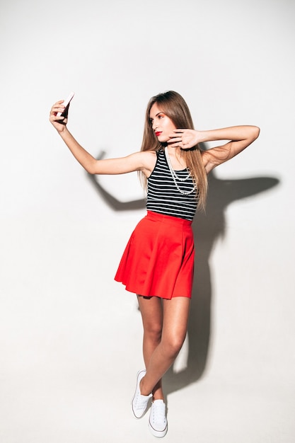 Stylish woman making selfie on mobile phone isolated neutral