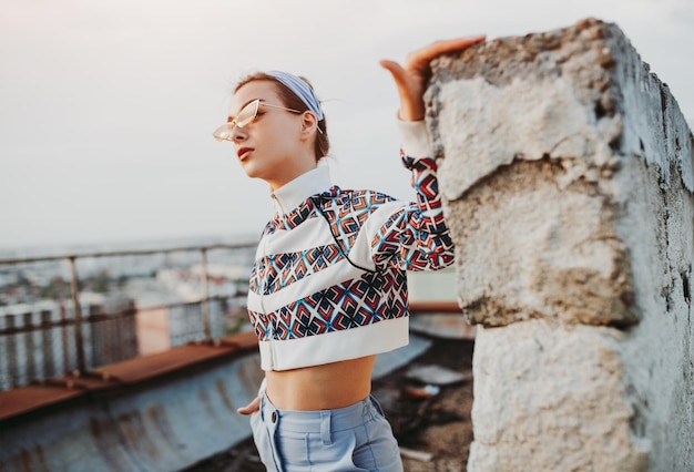 Stylish woman near crumbling wall on rooftop