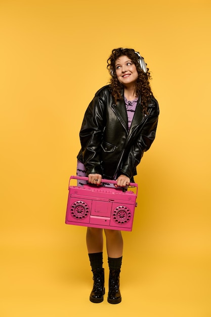 Stylish woman posing with boombox against yellow background