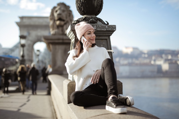 Stylish woman sitting on a bridge