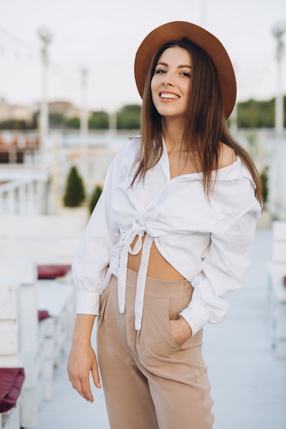 A stylish woman walks along the beachfront on a warm summer day in the sunset