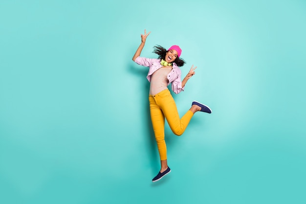 Stylish woman with afro hairstyle posing against the blue wall