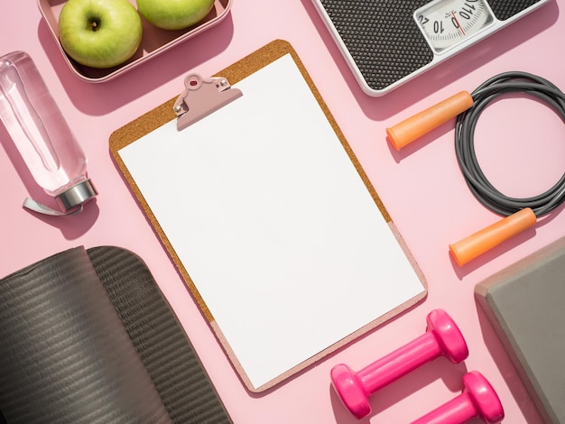 Photo stylish workout plan mockup in gray and pink colors fitness training flat lay top view of sport equipment water bottle scales and empty white sheet on clipboard on pink background copy space