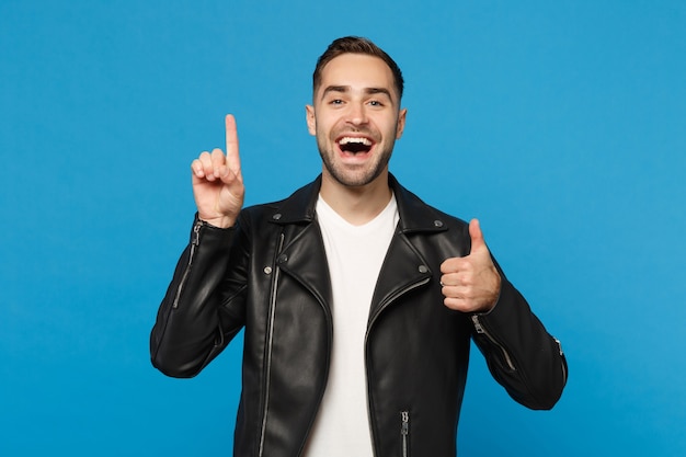 Stylish young bearded man in black leather jacket white t-shirt holding index finger up with great new idea isolated on blue background. People sincere emotions lifestyle concept. Mock up copy space.