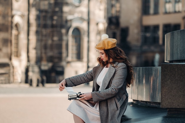 A stylish young beautiful girl is sitting and typing in the Old town of Dresden